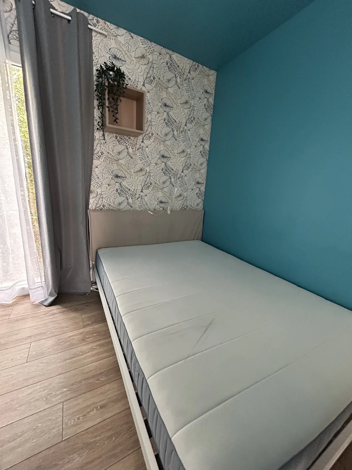 Coin nuit avec lit simple, papier peint floral et fenêtre