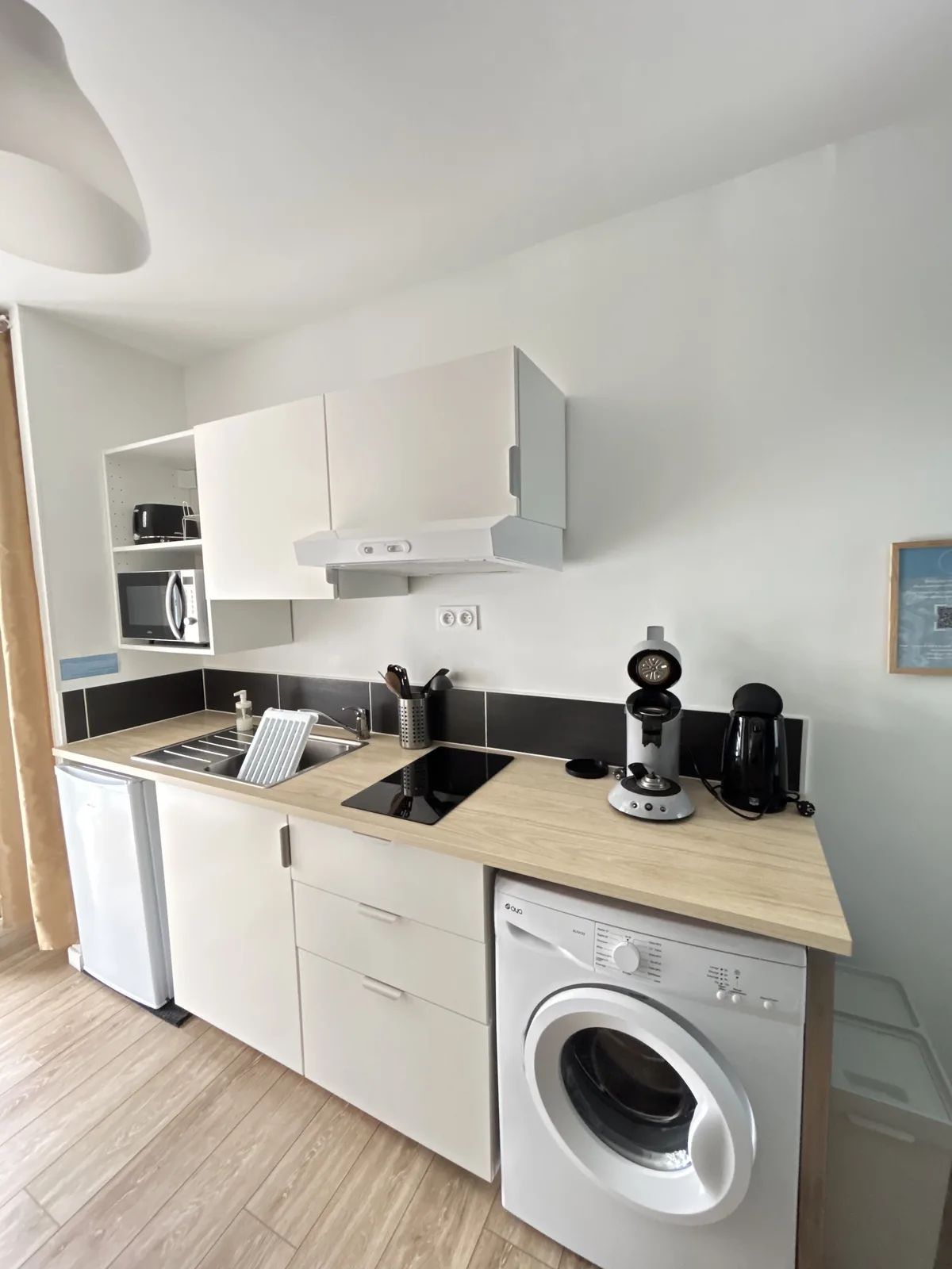 Kitchenette équipée : plaques, micro-ondes, hotte, réfrigérateur et lave-linge